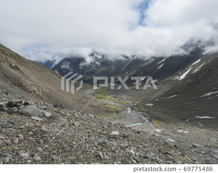 Summer view of alpine mountain valley with winding stream and glacial lake, Sulzenauferner Glacier, Stubai Alps, Austria 69775486