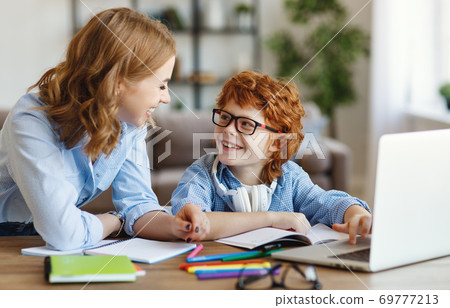 Mother helping child with online lesson at home. 69777213