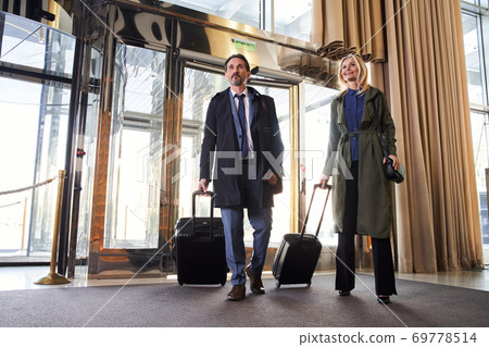 Two travelers with trolley bags entering the hotel hall 69778514
