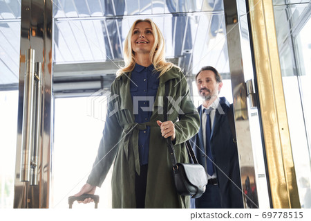 Mirthful couple entering the hotel and smiling 69778515