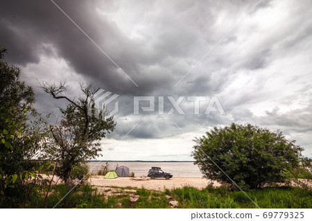 Black SUV with rooftop box near camping at the river. 69779325
