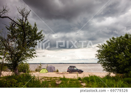 Black SUV with rooftop box near camping at the river 69779326