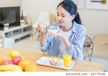 Young woman eating yogurt 69779396