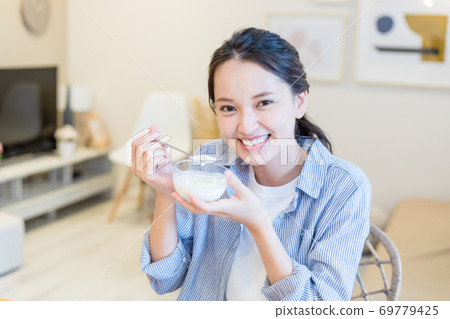 Young woman eating yogurt 69779425
