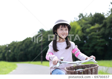 Girl practicing by taking training wheels on a bicycle 69780837
