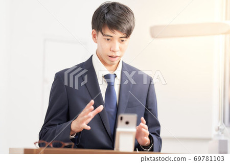 Male student undergoing a remote interview on a smartphone 69781103