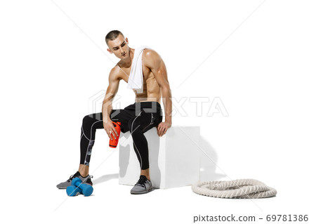 Beautiful young male athlete practicing on white studio background with shadows Beautiful young male athlete practicing on white studio background with shadows 69781386