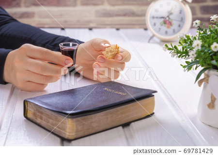 Young woman praying and Taking communion - the wine and the bread symbols of Jesus Christ blood and body with Holy Bible Young woman praying and Taking communion - the wine and the bread symbols of Jesus Christ blood and body with Holy Bible 69781429