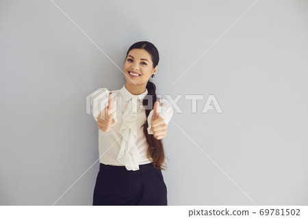 Young woman in white shirt smiling raised her thumb up happy positive on a gray background. Young woman in white shirt smiling raised her thumb up happy positive on a gray background. 69781502