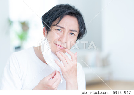 一個年輕人因為面膜而關心皮膚粗糙 一個年輕人因為面膜而關心皮膚粗糙 69781947