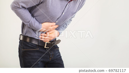A man suffers from abdominal pain. Abdominal pain. The guy in the seeming clothes holding belly with hands. 69782117