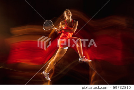 Professional female tennis player isolated on black studio background in mixed light Professional female tennis player isolated on black studio background in mixed light 69782810