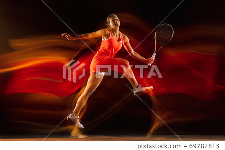 Professional female tennis player isolated on black studio background in mixed light Professional female tennis player isolated on black studio background in mixed light 69782813