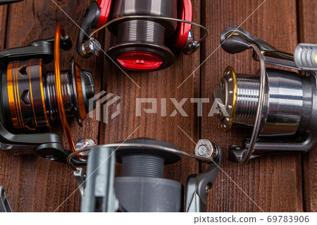 Different fishing tacles with lures and reels on wooden brown background with place for text. Different fishing tacles with lures and reels on wooden brown background with place for text. 69783906