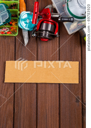Different fishing tacles with lures and reels on wooden brown background with place for text. Different fishing tacles with lures and reels on wooden brown background with place for text. 69783920