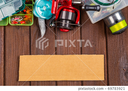 Different fishing tacles with lures and reels on wooden brown background with place for text. Different fishing tacles with lures and reels on wooden brown background with place for text. 69783921