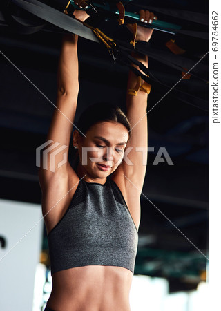 Functional training. Vertical shot of a young attractive sportive woman exercising on horizontal bar at gym 69784662