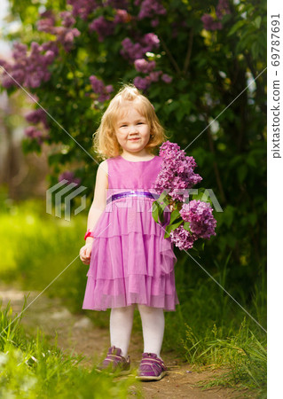 small girl near bush of lilac with a bouquet  69787691
