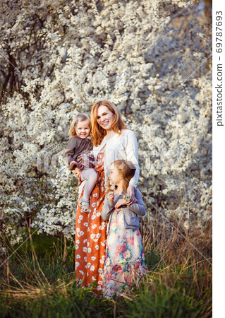 mom with two kids by bush with white flowers mom with two kids by bush with white flowers 69787693