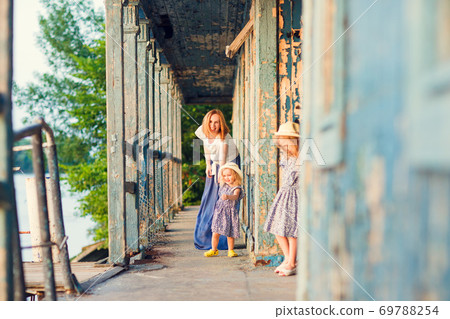 mom and kids standing on porch of old wooden house 69788254