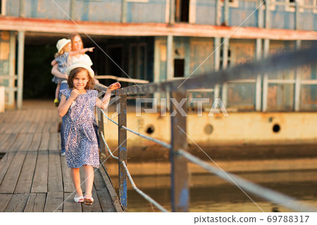 kid girl with mom and sister standing old bridge 69788317