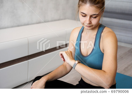 Portrait of young woman checking digital fitness tracker 69790006