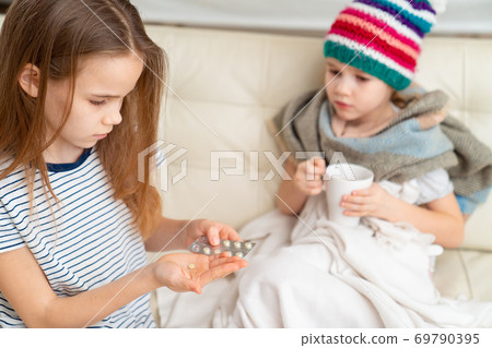 big sister giving medicine of sick younger big sister giving medicine of sick younger 69790395