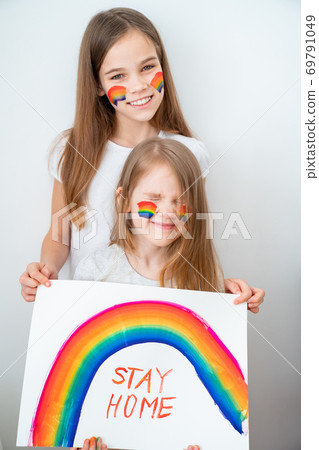 two funny girls drew rainbow and poster stay home. two funny girls drew rainbow and poster stay home. 69791049