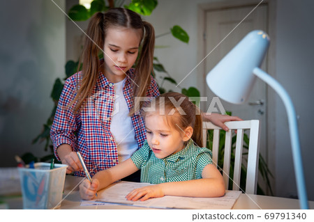 older sister helps younger with their writings 69791340