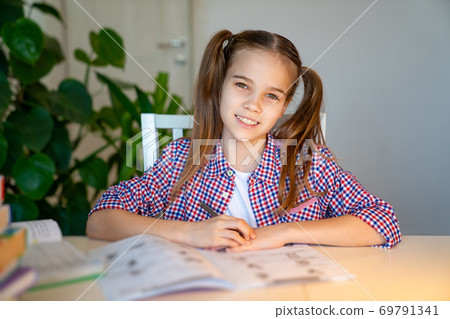 teen schoolgirl in a plaid shirt doing homework  69791341