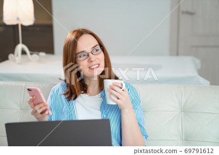 happy woman drink tea and read messages. 69791612