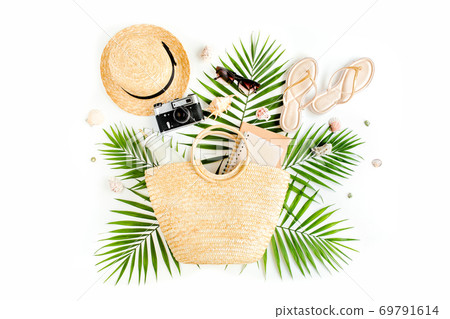 Woman's beach accessories: rattan bag, straw hat, tropical palm leaves on white background. The concept of travel. Woman's beach accessories: rattan bag, straw hat, tropical palm leaves on white background. The concept of travel. 69791614