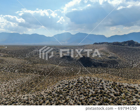 Aerial view of dusty dry desert land and mountain on the background in Lee Vining 69794150