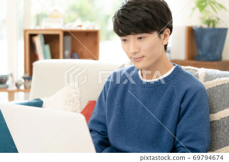 A man looking at a computer [Living room] 69794674