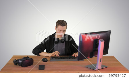 Gamer playing a video game on personal computer on gradient back 69795427