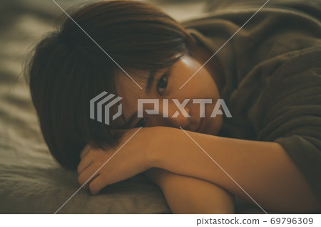 Woman in pajamas lying on the bed Woman in pajamas lying on the bed 69796309