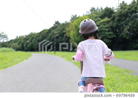 Girl practicing by taking training wheels on a bicycle 69796489