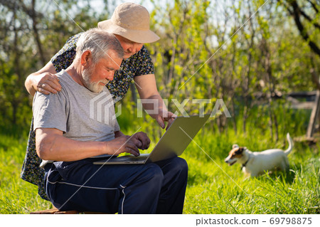 Elderly man and woman with a laptop in village 69798875