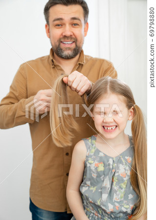 dad makes ponytails of her little daughter dad makes ponytails of her little daughter 69798880