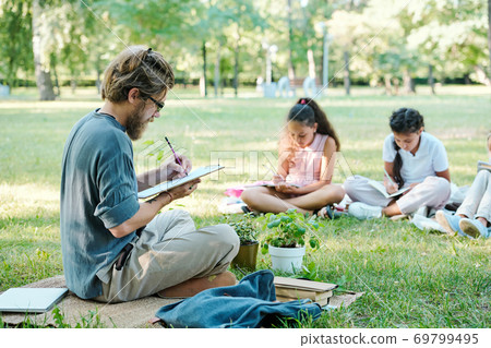 Teacher making notes while students doing tasks Teacher making notes while students doing tasks 69799495