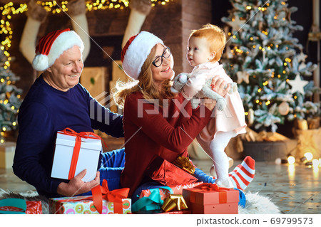 Grandmother and grandfather and girl are smiling in the house at Christmas. Grandmother and grandfather and girl are smiling in the house at Christmas. 69799573