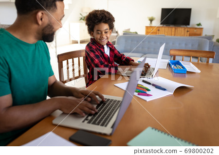 Father and son using laptop at home 69800202