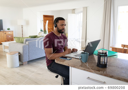 Man wearing headphones using laptop at home Man wearing headphones using laptop at home 69800208