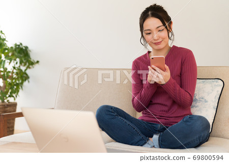 A woman operating a smartphone on the sofa during telework A woman operating a smartphone on the sofa during telework 69800594