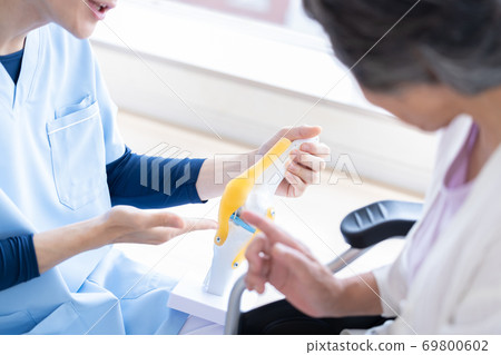 Medical doctor explaining using a knee joint model 69800602