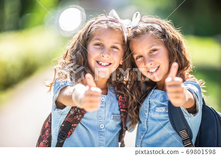 Twin sisters go back to school and showing thumbs up Twin sisters go back to school and showing thumbs up 69801598