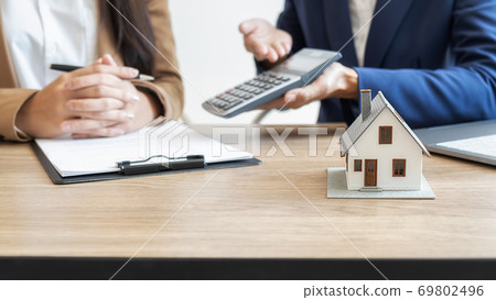 House model with agent and customer discussing for contract to buy, get insurance or loan estate. House model with agent and customer discussing for contract to buy, get insurance or loan estate. 69802496