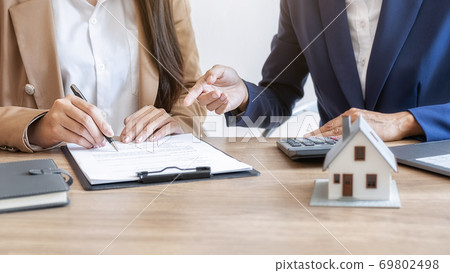 House model with agent and customer discussing for contract to buy, get insurance or loan estate. House model with agent and customer discussing for contract to buy, get insurance or loan estate. 69802498