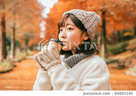 女人在冬季公園喝熱飲料 女人在冬季公園喝熱飲料 69803140
