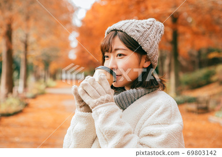 女人在冬季公園喝熱飲料 69803142
